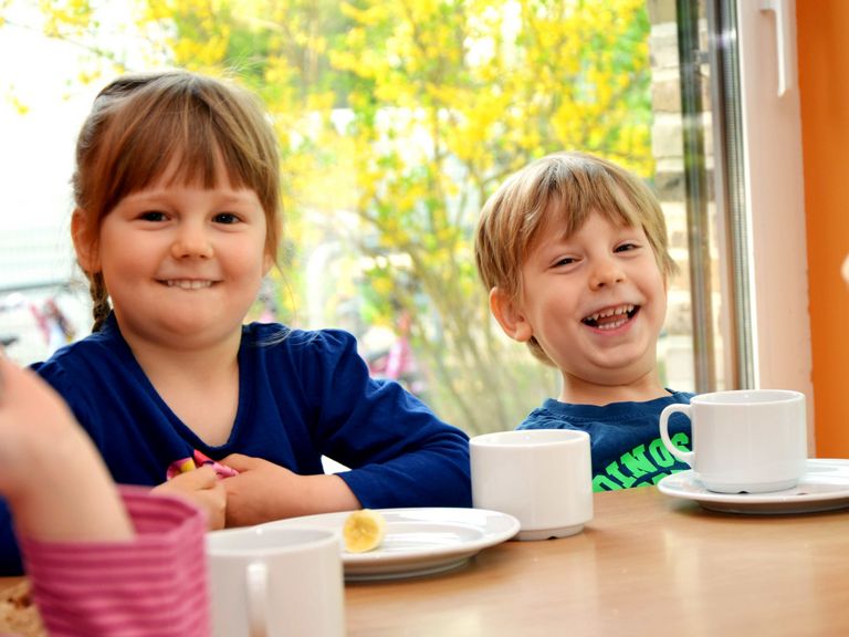 Zwei Kinder sitzen am Tisch und essen etwas, Speiseversorgung in der Kita, Kita-Mahlzeiten, Mittagessen im Kindergarten, Albertinen Kita Volksdorf in Hamburg