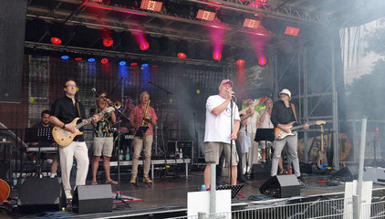 Eine Band mit Sänger und Bassisten spielt auf einer professionellen Musikbühne mit Scheinwerfern und Verstärkern beim Sommerfest 2026 auf dem Gesundheitscampus Volksdorf des Evangelischen Amalie Sieveking Krankenhauses, der Residenz am Wiesenkamp, des Feierabendhauses Volksdorf und der Albertinen Kindertagesstätte Volksdorf. 