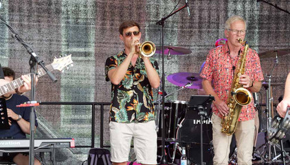 Ein Trompeter und ein Saxophonist spielen in bunten Hemden auf der Musikbühne beim Sommerfest 2026 auf dem Gesundheitscampus Volksdorf des Evangelischen Amalie Sieveking Krankenhauses, der Residenz am Wiesenkamp, des Feierabendhauses Volksdorf und der Albertinen Kindertagesstätte Volksdorf. 